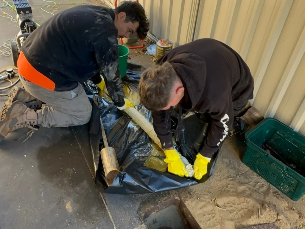 Four Plumbed Right technicians standing in front of the drain relining truck and two signwritten work utes