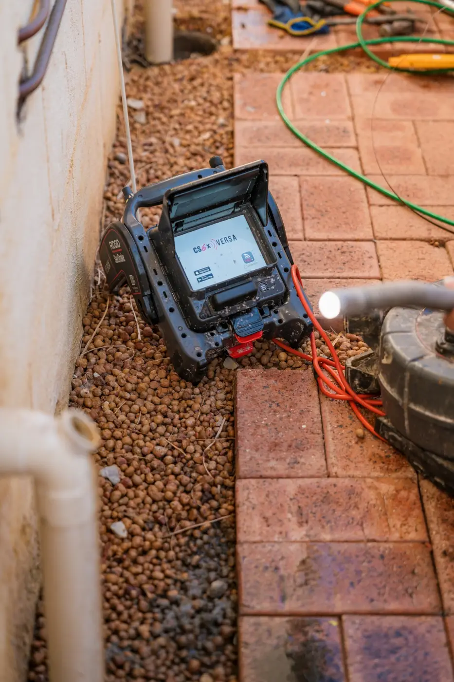 CCTV monitor on gravel with the camera cable running into the drain