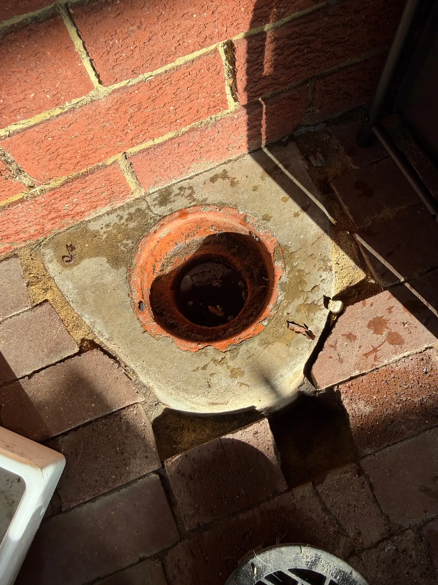 Clay drain gully riser set in brick paving at a Craigie job, the grate lifted