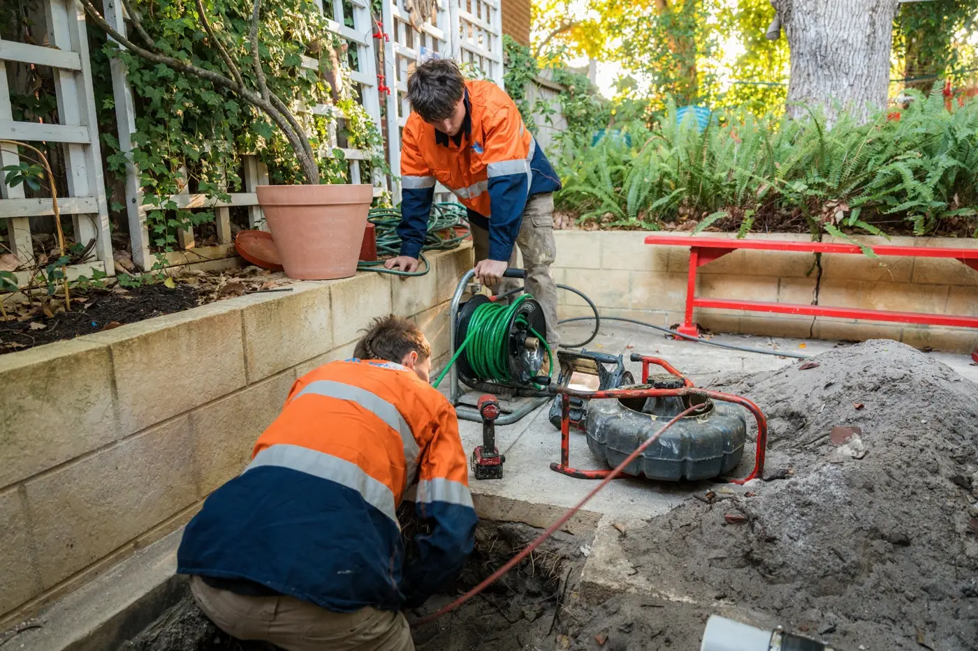 Two Plumbed Right techs at an open drain pit with the CCTV reel