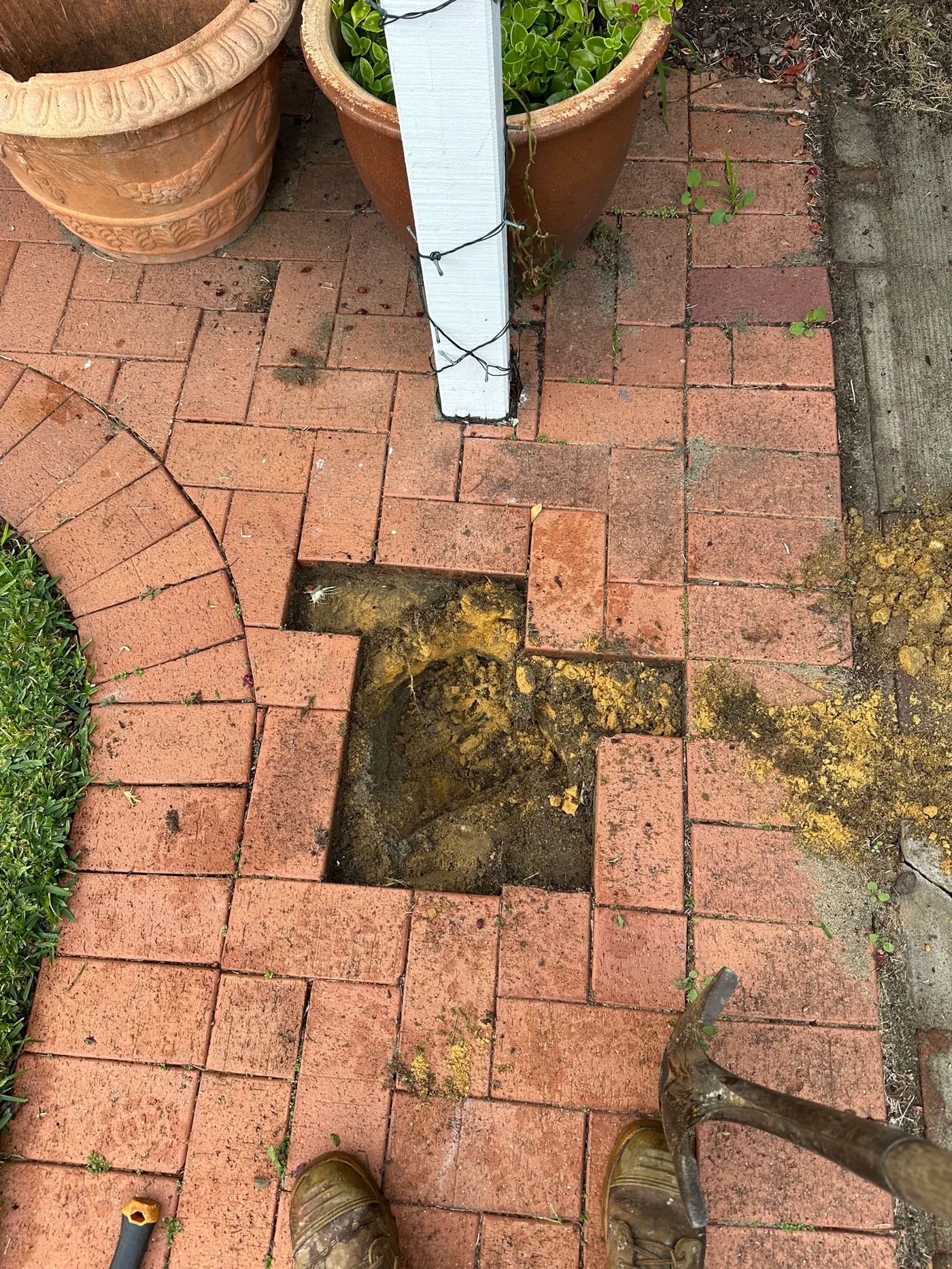 Brick pavers lifted and a hole dug down to reach the drain line