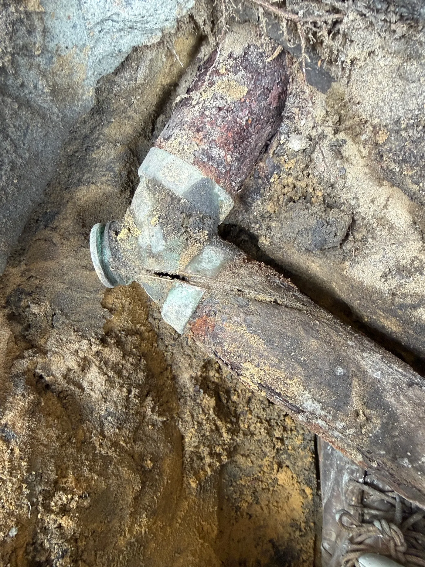 Corroded galvanised drain pipe and cracked fitting dug out from under a concrete slab