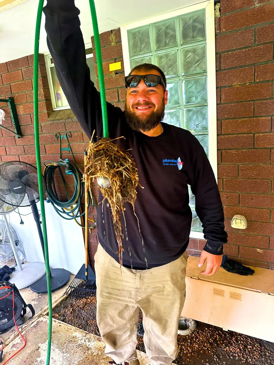 Tech holding up a root ball pulled out of a drain on the cable