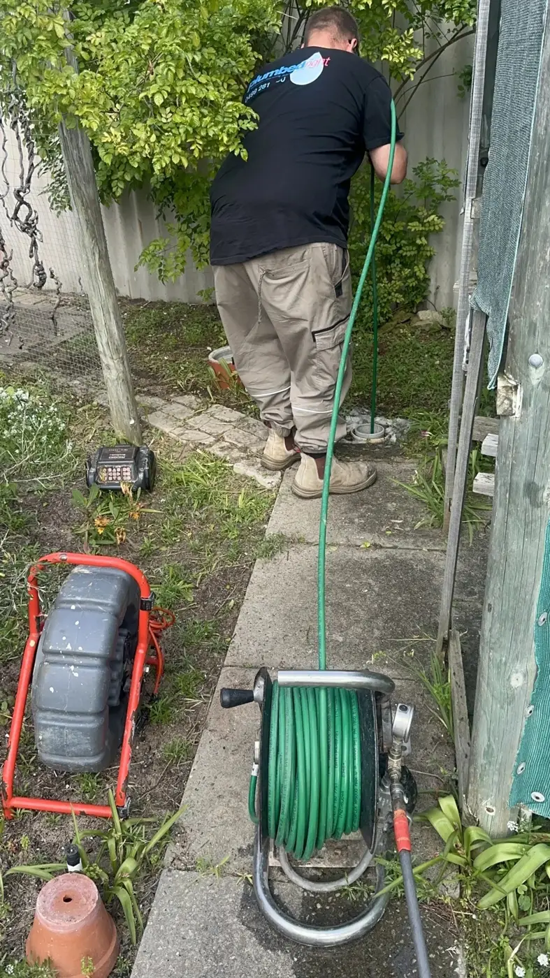 Tech walking a side path with a hose reel and a red CCTV reel