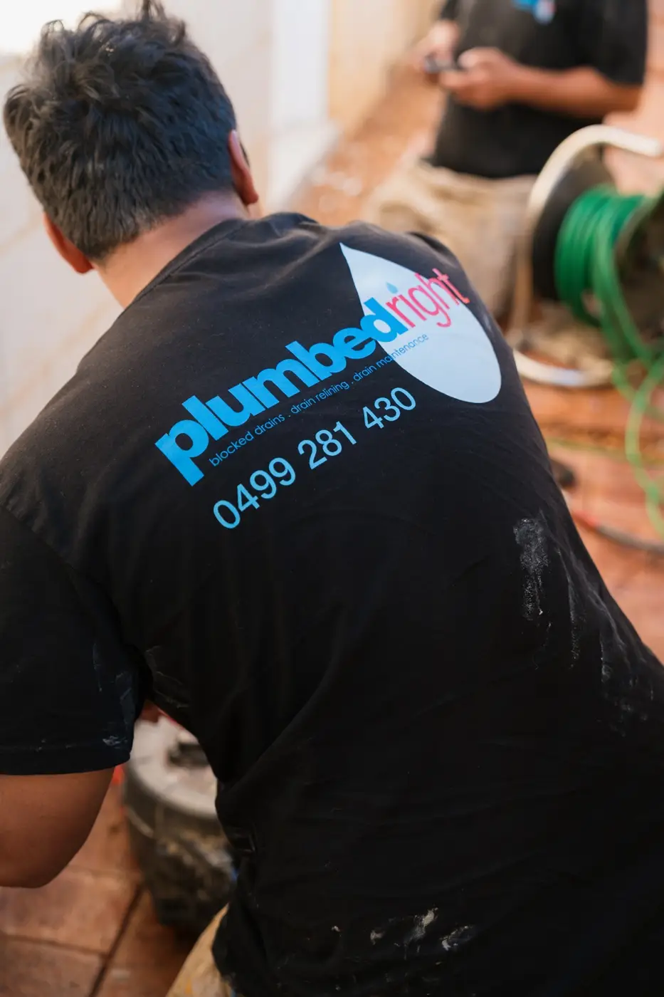 Plumbed Right tech at work, logo and 0499 281 430 on the back of his shirt