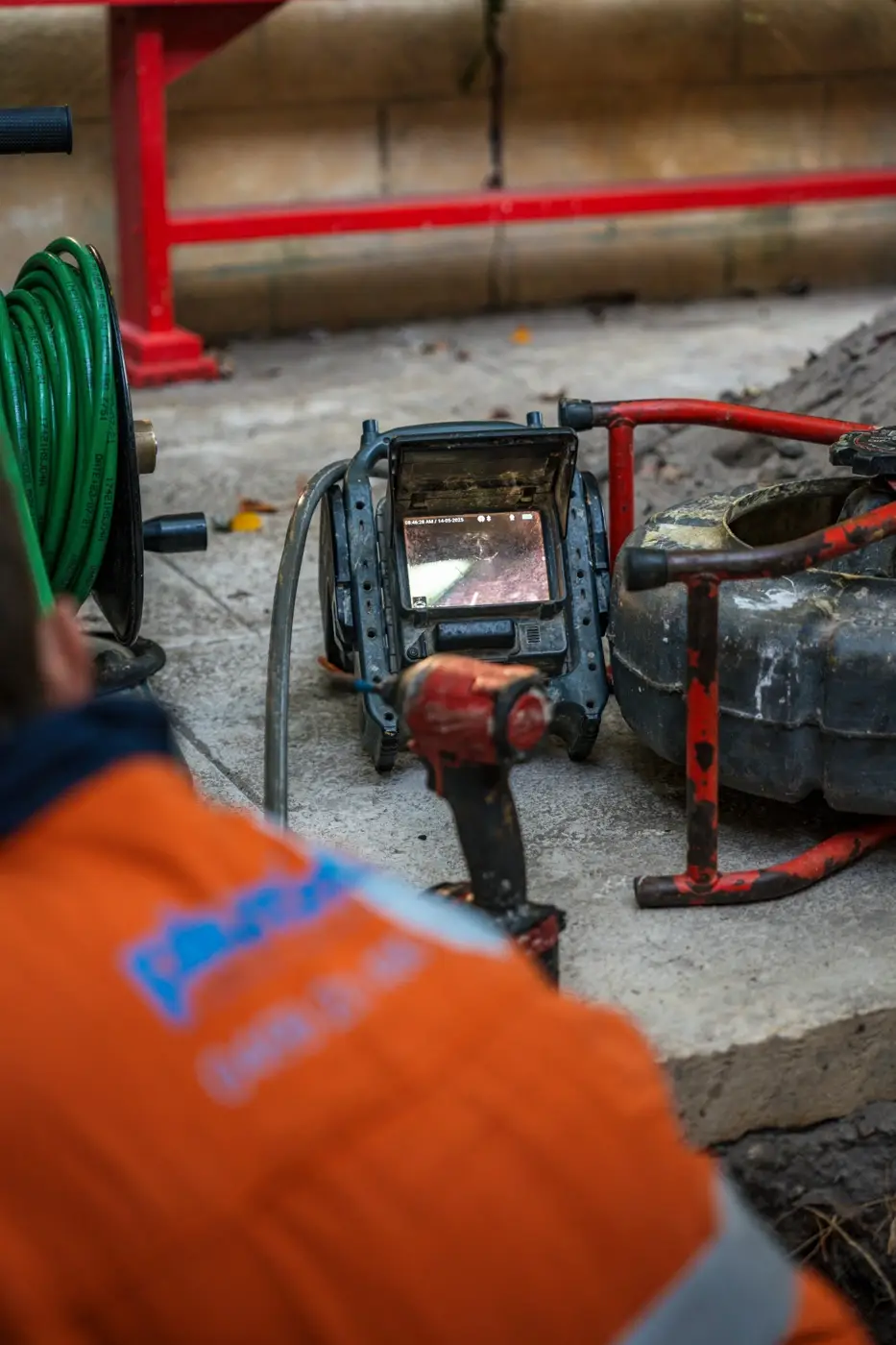 Back of an orange Plumbed Right hi-vis shirt beside a CCTV monitor